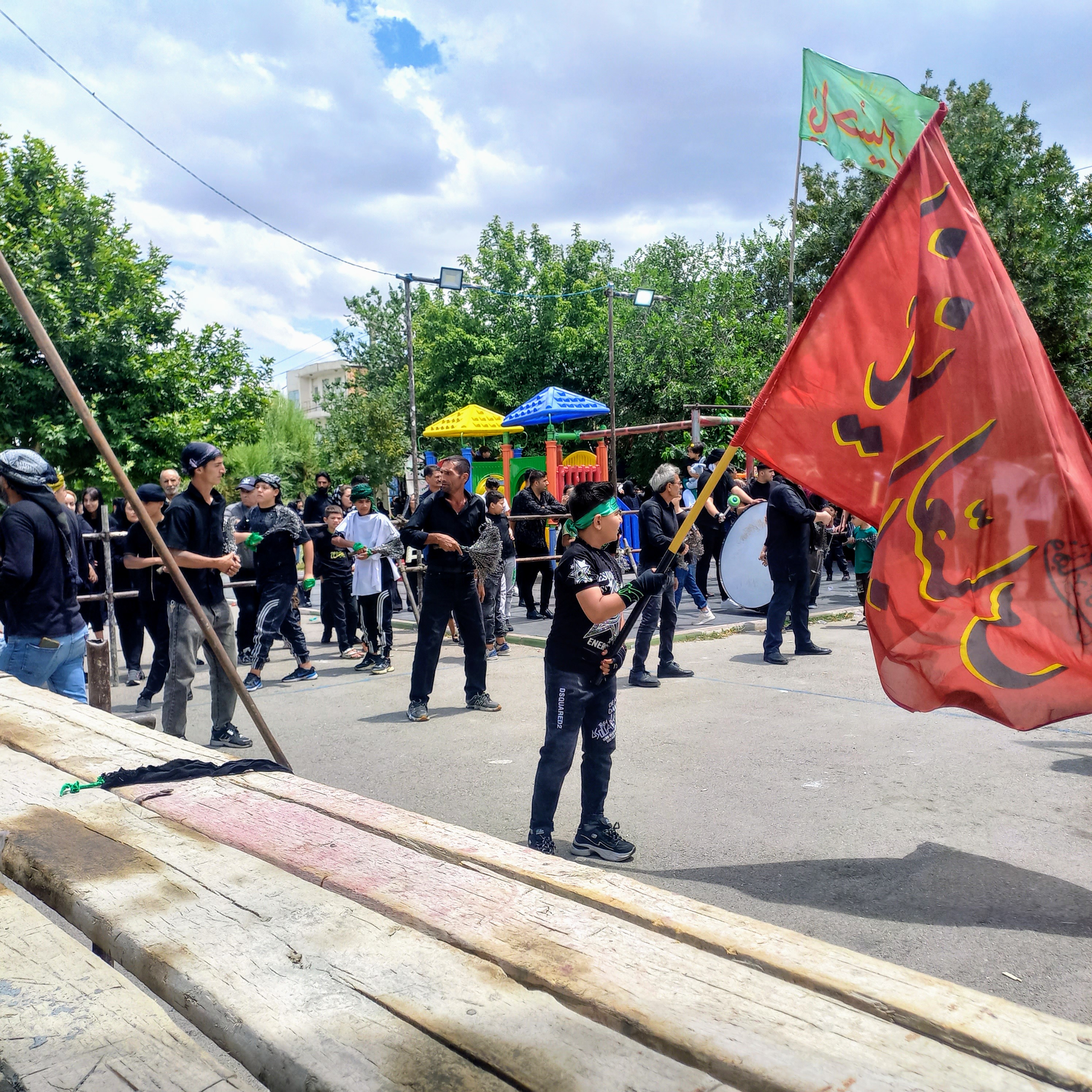 در بوستان صفا، میان وسایل بازی کودکان، دسته عزاداران حسینی صف کشیده‌اند. پرچم سرخ «یا ابالفضل العباس» و پرچم سبز «یا حسین»در باد می‌رقصند و کودکی سیاه‌پوش با نگاهی پر از معرفت، پرچم را بالا نگه داشته است؛ اینجا عشق به امام حسین (ع) از کودکی آغاز می‌شود.تاسوعای حسینی | ۲۵ تیر ۱۴۰۳ | ارومیه، بوستان صفا 🖤 یا حسین(ع)