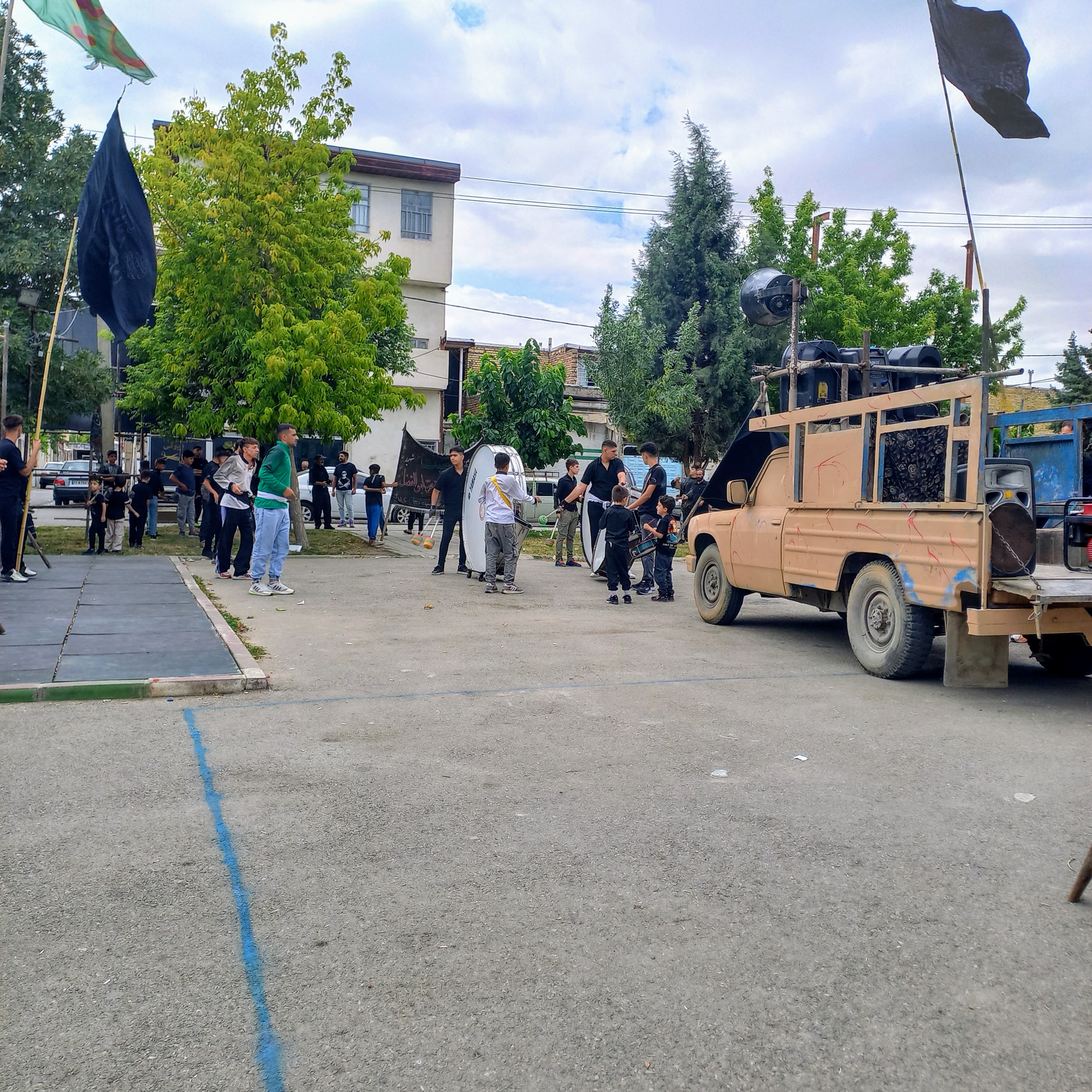 در روز عاشورا، وانت پر از بلندگو و طبل‌های عزا در بوستان صفا توقف کرده و نوای روضه و مرثیه در فضا پیچیده است. عزاداران سیاه‌پوش دور هم جمع شده‌اند، پرچم‌های سیاه و سبز برافراشته و کودکان نیز با شور حسینی در این مجلس عزا شرکت جسته‌اند؛ این صحنه، یادآور زنده ماندن ماتم اباعبدالله (ع) در دل‌های عاشقان است.عاشورا حسینی | ۲۶ تیر ۱۴۰۳ | ارومیه، بوستان صفا 🖤  یا حسین  (ع)