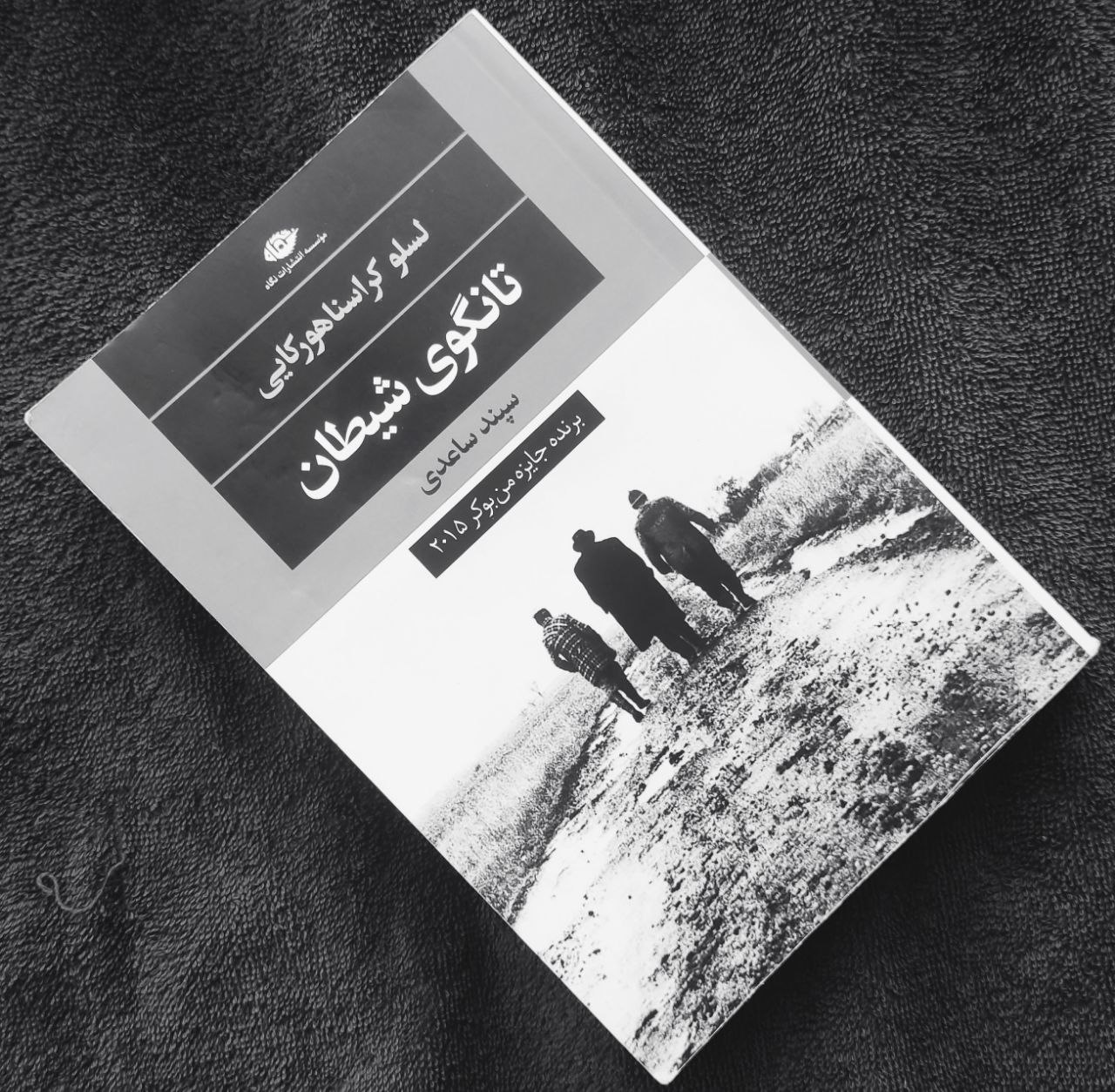 در این جهان، حتی معجزه هم چیزی را تغییر نمی‌دهد.جنازه بالا می‌رود، اما شیطان همچنان به راهش ادامه می‌دهد، و باران هنوز می‌بارد.بارانِ بی‌وقفه‌ی پاییزی می‌بارد. گل و لای همه‌جا را گرفته.ناقوس می‌نالد، اما برای چه؟ هیچ‌چیز در اینجا زنده نیست؛ سقف‌ها فروریخته، درها پوسیده، و امید مدفون شده است.در این روستای فراموش‌شده، توده‌ای از انسان‌های خسته و درمانده هنوز مانده‌اند؛ مردمی که نه کاری دارند، نه نانی، نه امیدی.تا آنکه روزی «نجات‌دهنده‌شان» بازمی‌گردد؛ مردی که گمان می‌کردند مرده است. او همچون پیامبری میان آنان می‌آید و از رستگاری سخن می‌گوید.اما آیا این پیامبر همان شیطان نیست؟ آیا قرار است آنان را از چاله‌ای که در آنند، به چاهی عمیق‌تر بیندازد؟در جایی که پاک سرشتی دور انداخته شده و مرده چه چیزی مهم است و مگر انسان آواره که نه خانه‌ای درست برای زندگی کردن دارد و نه کاری دارد نه خوراک، برایش مهم است که در آینده چه اتفاقی خواهد افتاد و چه بلایی ممکن است بر سرش فرو ریزد؟اما برای همه اینگونه نبود فوتاکی که مردی معلول اما باهوش بود قصه را اینگونه روایت میکند «کل ماجرا به چشم او بیشتر به رمیدن گله‌ای می‌ماند. گریزی، کورکورانه و بیهوده به سمت مقصدی نامعلوم».تانگوی شیطان نوشتهٔ لاسلو کراسناهورکایی، تصویری است از جهانی در آستانه‌ی فروپاشی؛ جایی میان خیال و واقعیت، که انسانِ ناامید در انتظار نجات، خود به دام فریب می‌افتد.اگر دوست دارید ادبیاتی بخوانید که مرز میان امید و تباهی را در هم می‌شکند، این کتاب تجربه‌ای فراموش‌نشدنی است.بصورت خودمونی  بگم واقعا با این کتاببب کیف کردم توصیفایی که بکار برده، شخصیت پردازیایی که کرده و اینکه اصلا شما نمیدونید دارید این داستان رو در مبنای واقعیت  میخونید یا همش توهم و خیاله.و پایانشم بدین صورته که چندین برداشت متفاوت میتونیم داشته باشیم