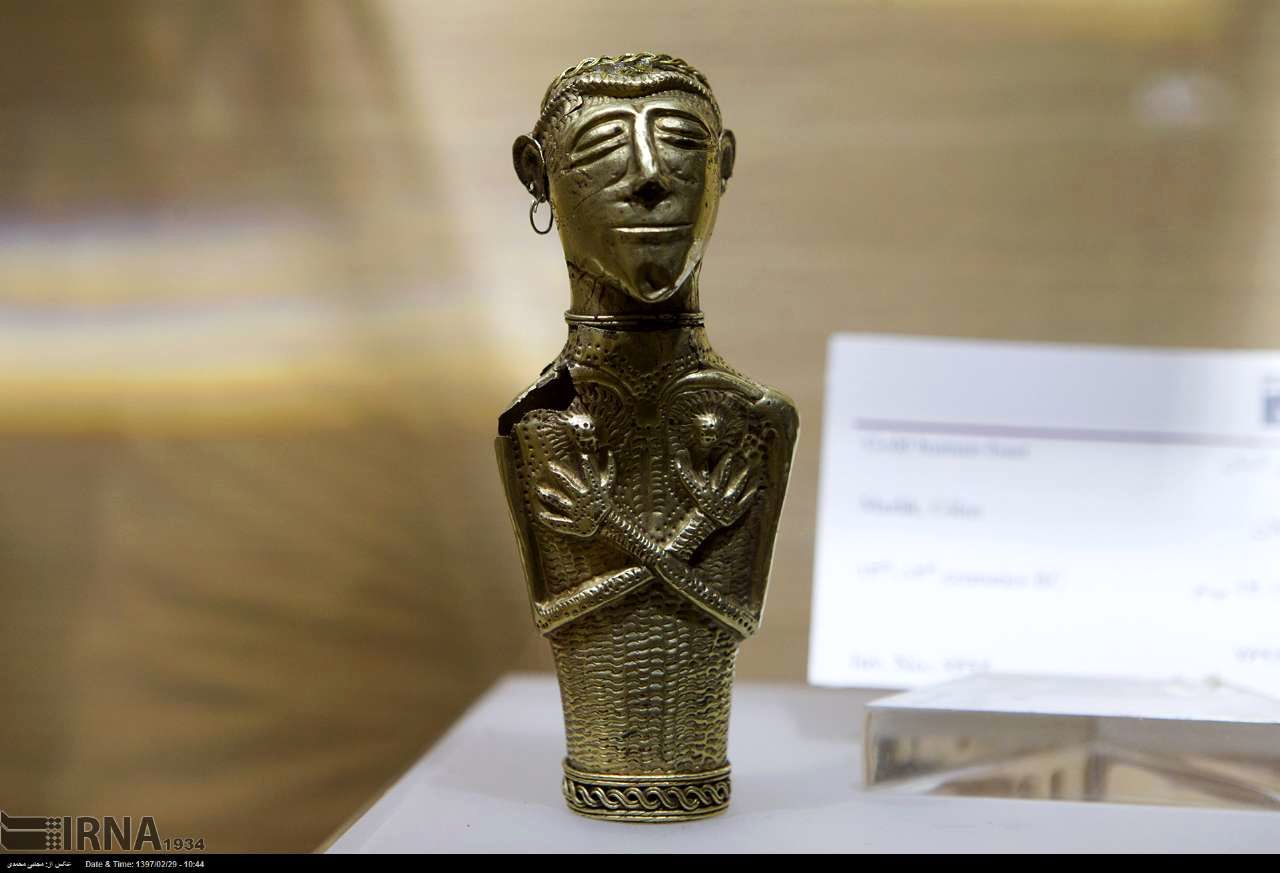 تندیس شخصی که لباس رسمی به تن دارد و یک گوشواره ی حلقه ای ساده بر یکی از گوشهایش باقی است، ارتفاع: 11.7 سانتی متر، وزن:43.5  گرم، قدمت: اواخر هزاره ی دوم یا اوایل هزاره ی نخست پیش از میلاد، منطقه ی جغرافیایی: مارلیک